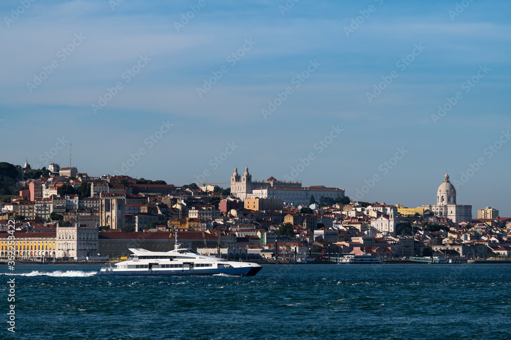 A passenger boat crossing the Tagus River (Rio Tejo) with the skyline of the downtown of the city of Lisbon on the background, in Portugal, Europe