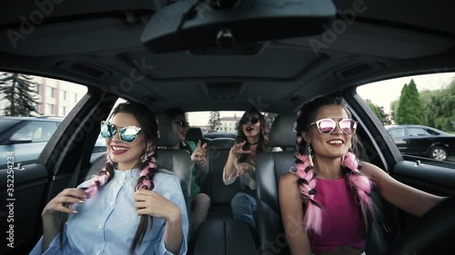 Stock video of four beautiful and funny girls in sunglasses dancing and singing the song listening to the radio. Pretty girls in sunglasses having fun driving the car in the city.