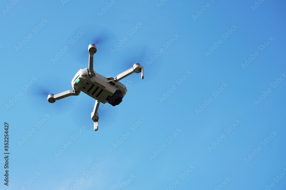 Drone in flight in motion against a blue sky Drone in flight in motion against a blue sky