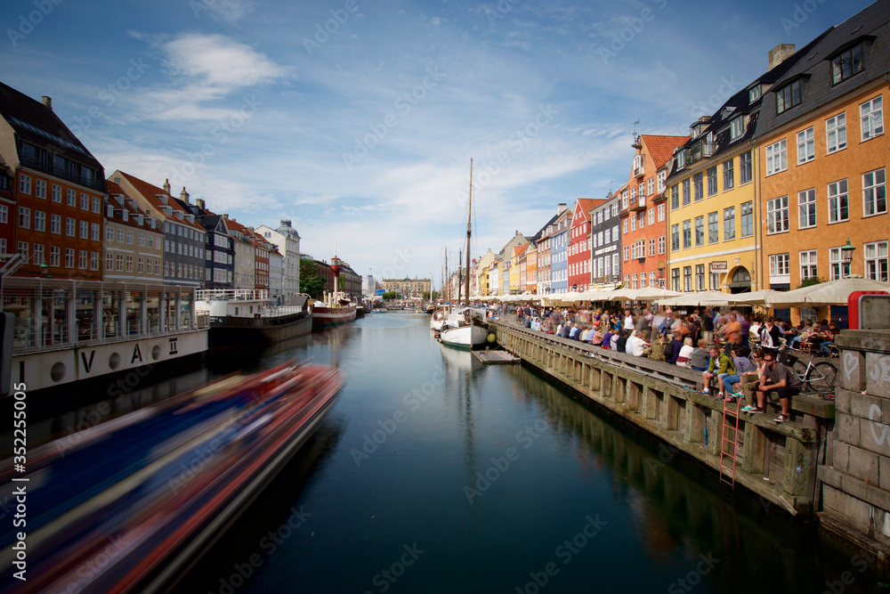 Scenic Nyhavn Pier With Tourists And Tour Boat In Copenhagen.