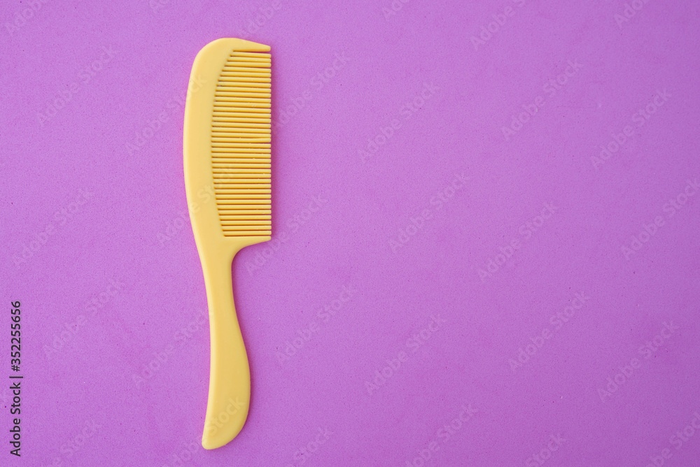 children's plastic hair comb yellow, pink background close-up children's plastic hair comb yellow, pink background close-up