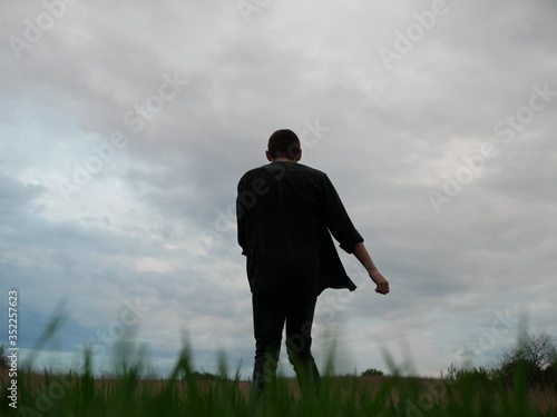 Man walking in a Meadow. Green field in the summer on morning day, Young man walking in the field, alone.