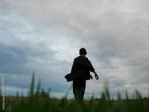 Man walking in a Meadow. Green field in the summer on morning day, Young man walking in the field, alone.