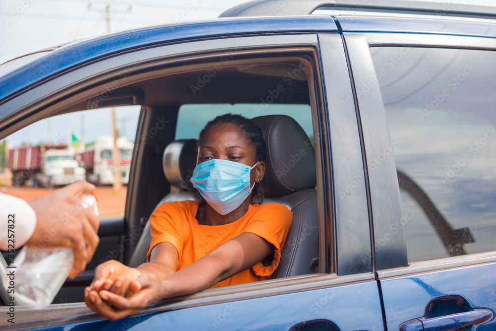 Woman in a car receiving alcohol gel or sanitizer gel for washing hands, corona virus or Covid-19 protection.