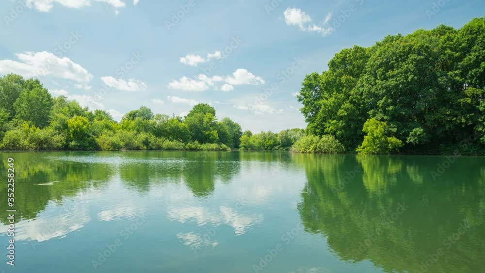 City park located in Milan, Italy, called “Bosco in città” (meaning: forest in the city). The clip shows a small lake, green trees and blue sky with moving clouds in the background – hyper lapse City park located in Milan, Italy, called “Bosco in città” (meaning: forest in the city). The clip shows a small lake, green trees and blue sky with moving clouds in the background – hyper lapse