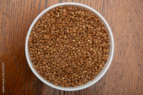 Buckwheat in a white Cup on a brown table.