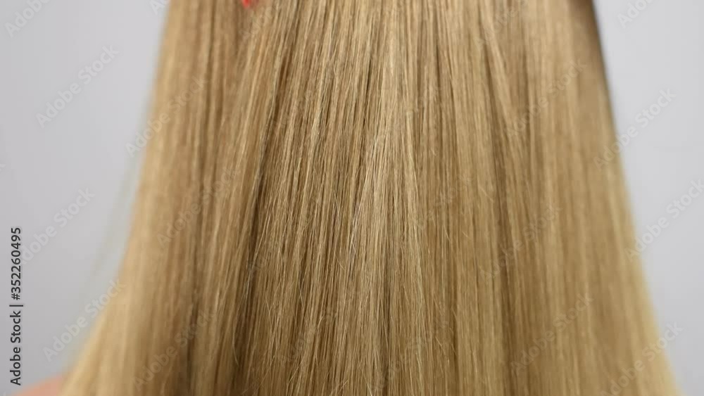 Hand is combing healthy long straight hair. Haircare. Beautiful and smooth blonde hair. Hand is combing healthy long straight hair. Haircare. Beautiful and smooth blonde hair.