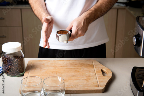 Man arranging coffee ground powder into portafilter basket at home