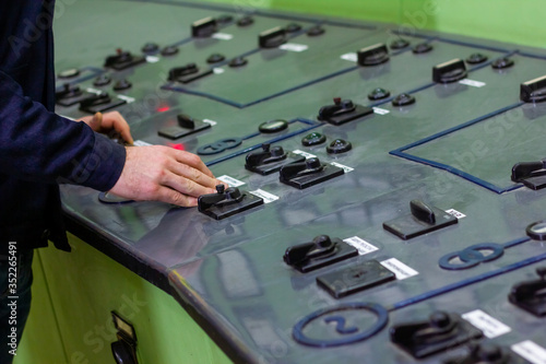 hands of a man on control panel in factory