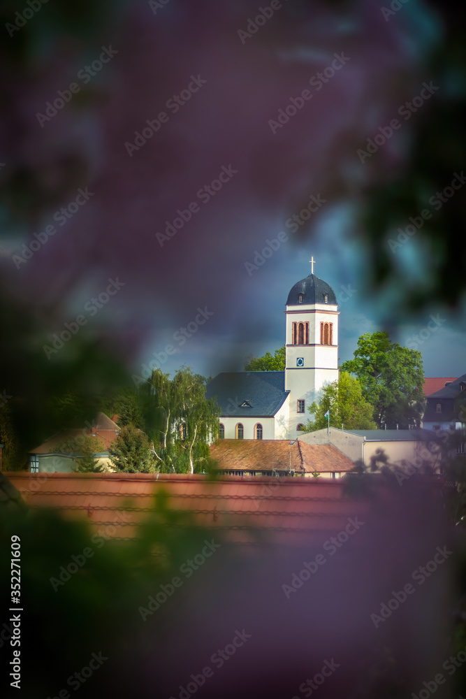Kirche, Kirchturm, Dorf, vor Gewitterhimmel, mit Flieder, unscharf im Vordergrund, eingerahmt,  dramatisch, Mosel, Zwickau, Sachsen, Deutschland