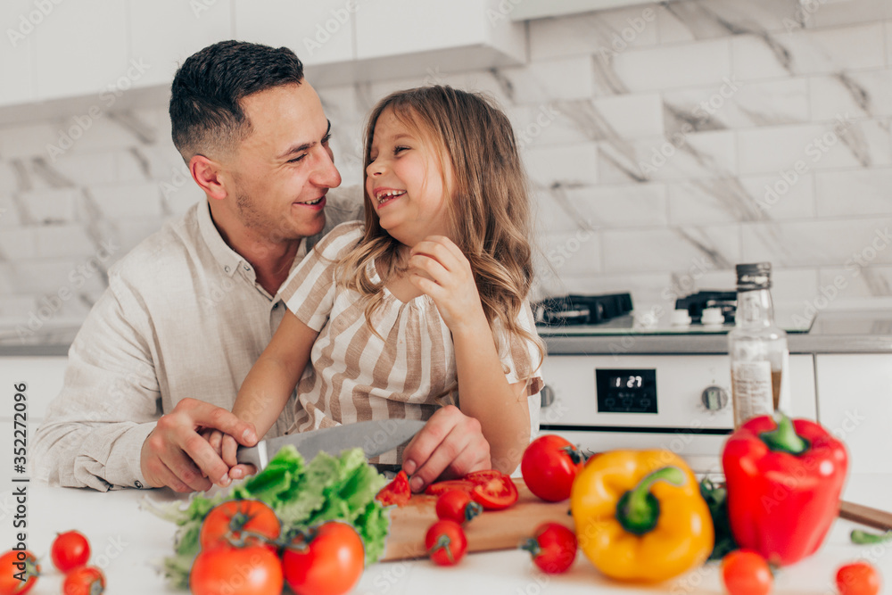 Father's day. Dad and his child daughter are cooking and having fun together in the kitchen. Family holiday. Father's day. Dad and his child daughter are cooking and having fun together in the kitchen. Family holiday.