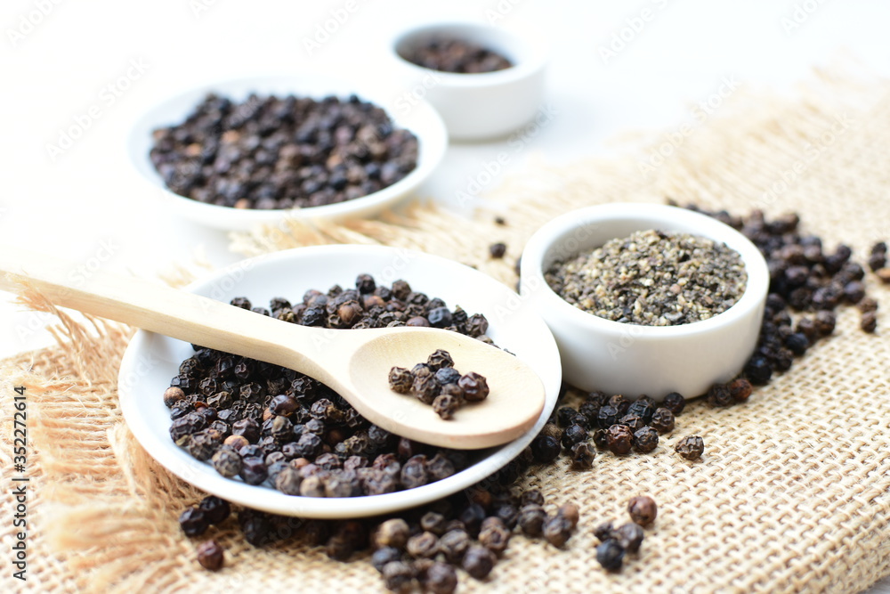 Black peppercorns in bowls on white wooden background Black peppercorns in bowls on white wooden background