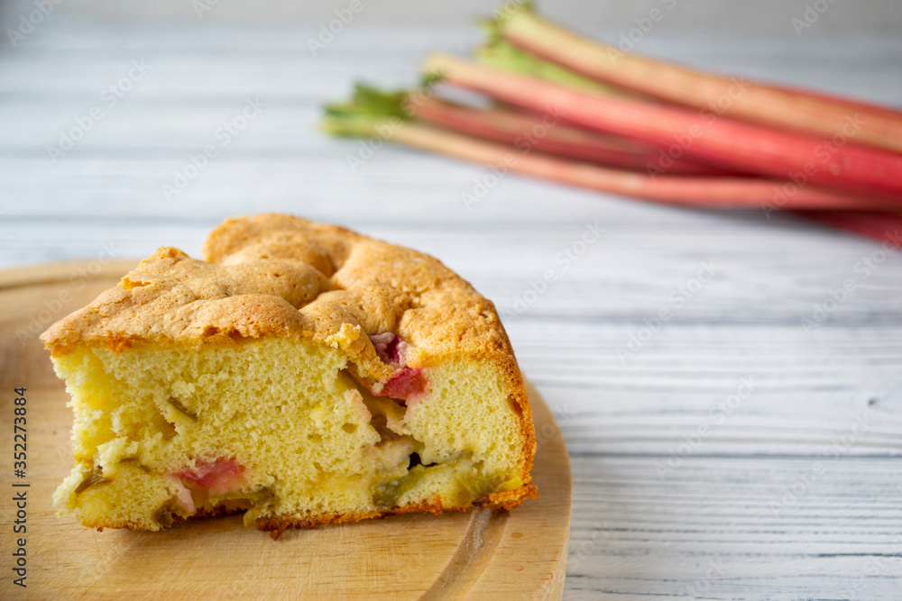 A piece of sponge cake with rhubarb on a white wooden background A piece of sponge cake with rhubarb on a white wooden background