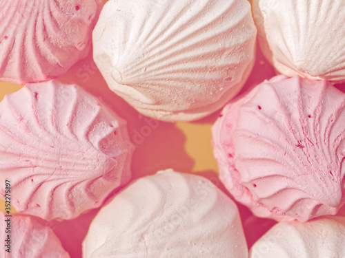 Fototapeta Naklejka Na Ścianę i Meble -  Pink and white marshmallows are close together on a platter. Cracks and pieces of sugar are visible on the surface of sweets. Culinary concept.