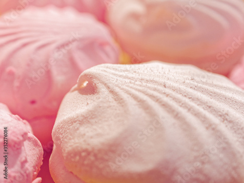 Pink and white marshmallows are close together on a platter. Cracks and pieces of sugar are visible on the surface of sweets. Culinary concept.