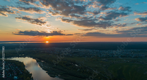 Panoramic aerial view of the nature landscape with green meadows and a river at sunset.