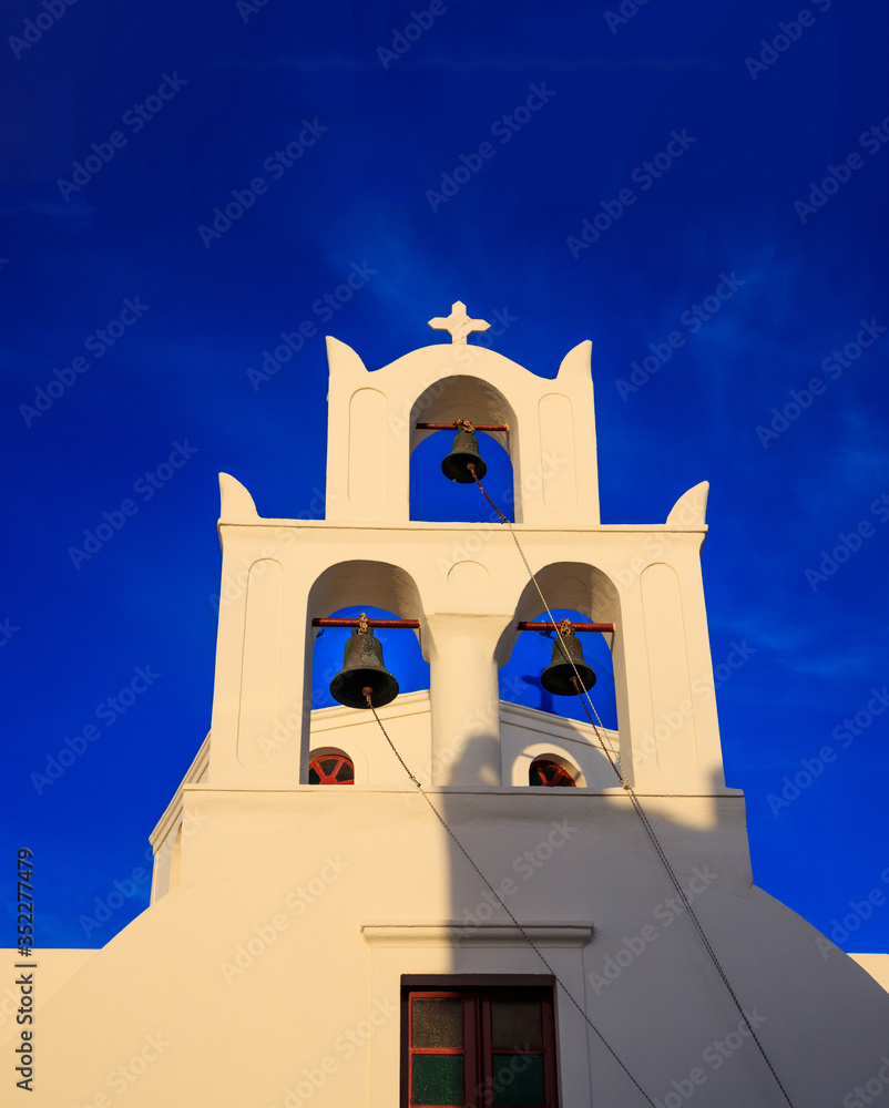 Santorini, Greece. White church and bells against blue sky background.