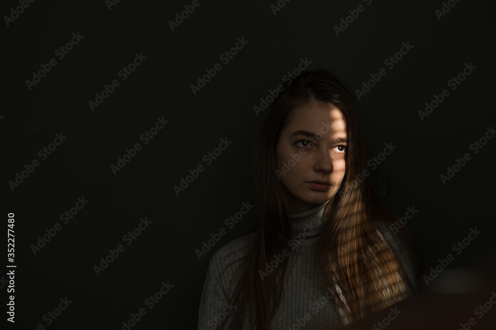 portrait of a girl against a dark background, the light from the window falls on the girl’s face, I create shadow stripes on the blinds portrait of a girl against a dark background, the light from the window falls on the girl’s face, I create shadow stripes on the blinds
