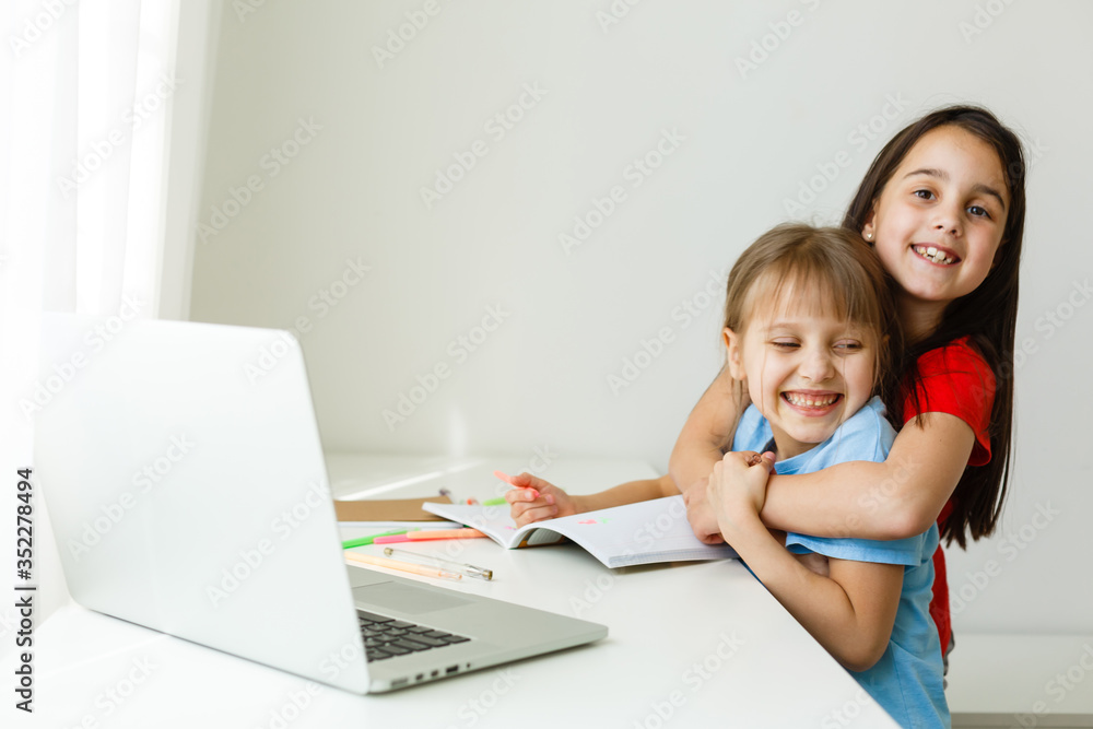 Cool online school. Kids studying online at home using a laptop. Cheerful young little girls using laptop computer studying through online e-learning system. Distance or remote learning Cool online school. Kids studying online at home using a laptop. Cheerful young little girls using laptop computer studying through online e-learning system. Distance or remote learning