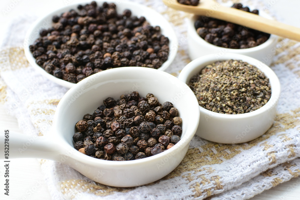Whole and ground black peppercorns on white wooden background Whole and ground black peppercorns on white wooden background