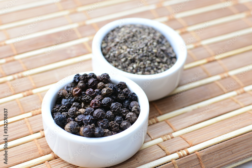 Whole and ground black peppercorns on white wooden background Whole and ground black peppercorns on white wooden background