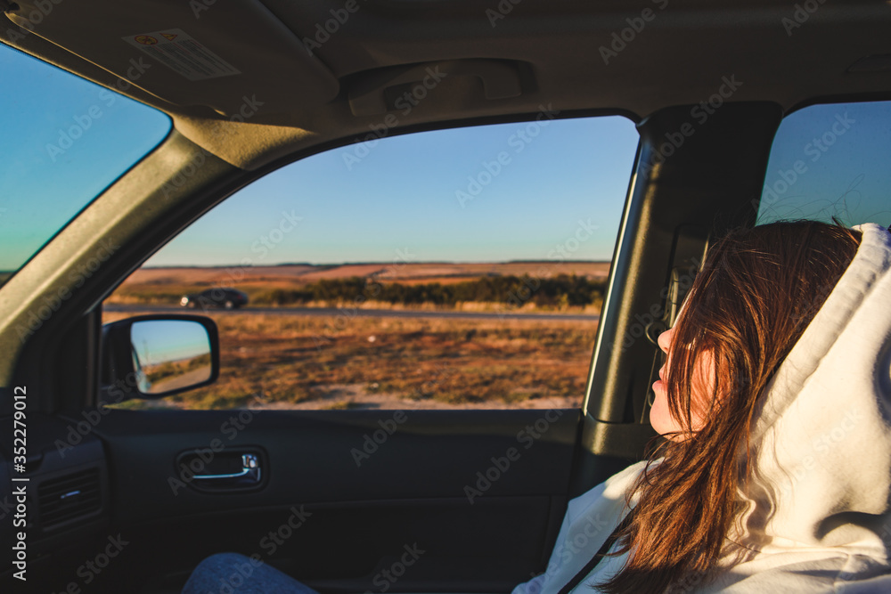 woman sitting in car looking at road. sunset time