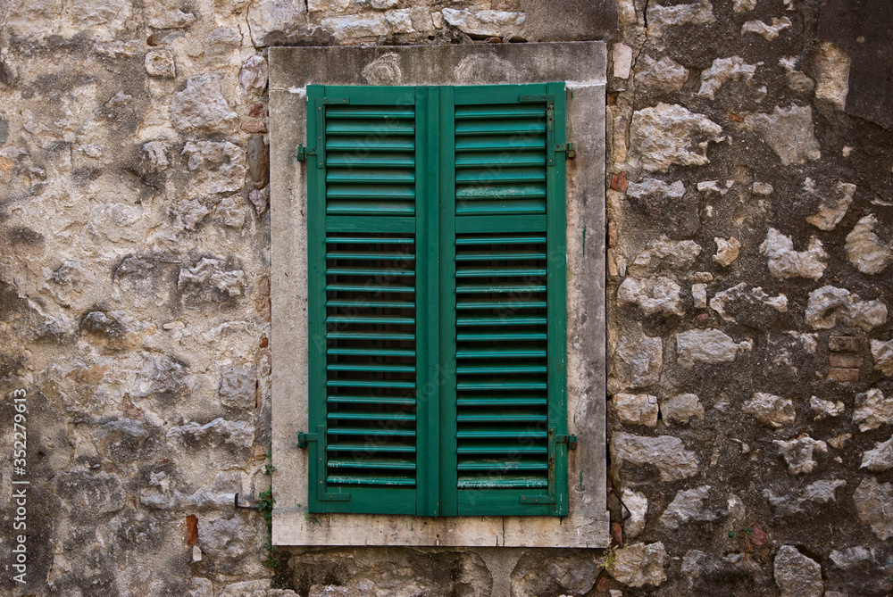 A window closed by wooden shutters-blinds green colour A window closed by wooden shutters-blinds green colour