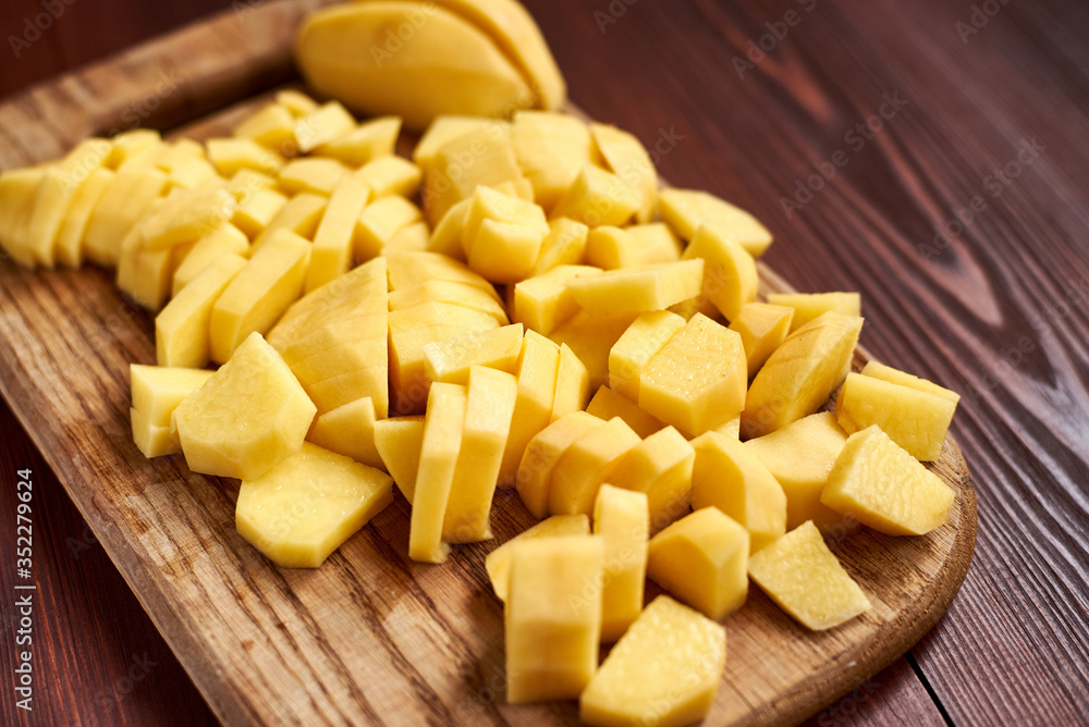 peeled sliced raw potatoes on a wooden board. Preparing vegetables for cooking. peeled sliced raw potatoes on a wooden board. Preparing vegetables for cooking.