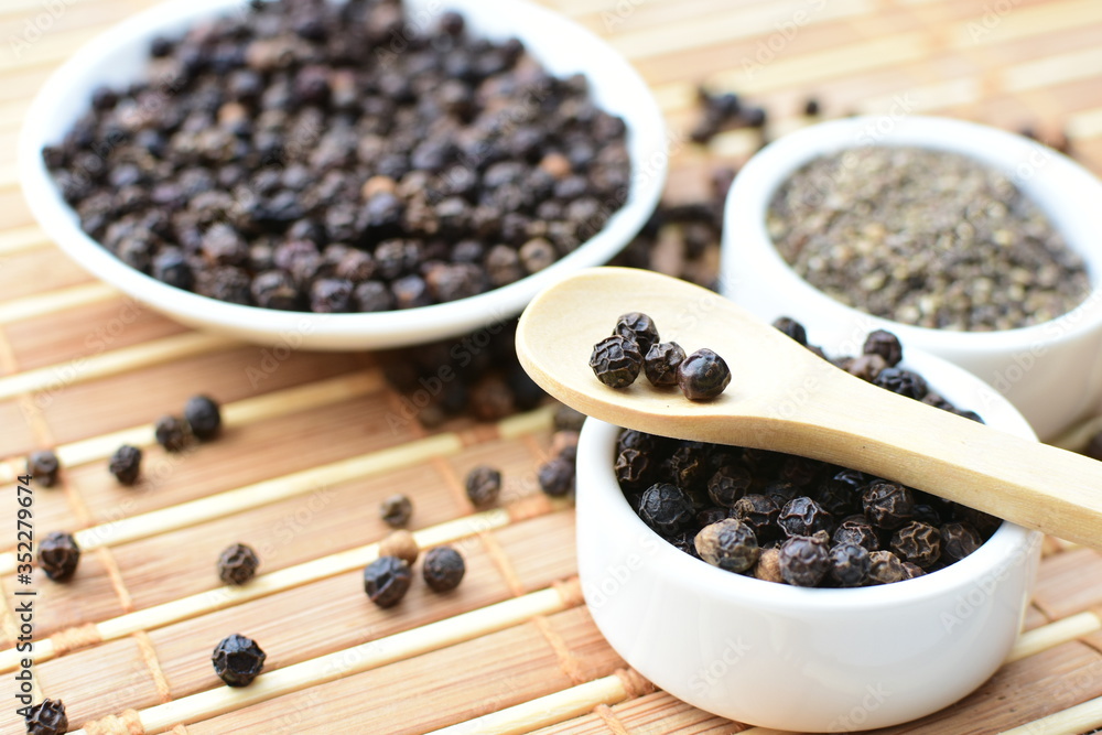 Whole and ground black peppercorns on white wooden background Whole and ground black peppercorns on white wooden background