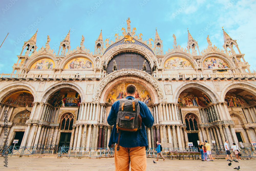 tourist man with backpack standing in front of saint marco basilica Venice, Italy