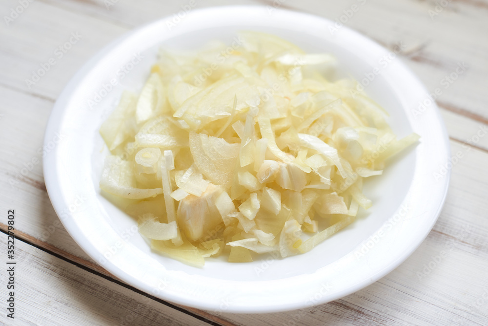 Sliced onions on a plate on a wooden background. Preparing for the recipe.