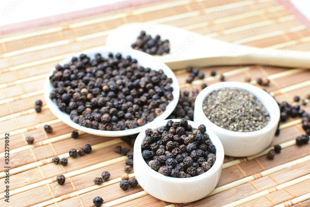 Whole and ground black peppercorns on white wooden background Whole and ground black peppercorns on white wooden background