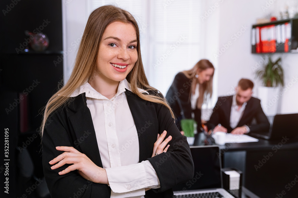 Portrait of confident business woman standing in office with her Portrait of confident business woman standing in office with her