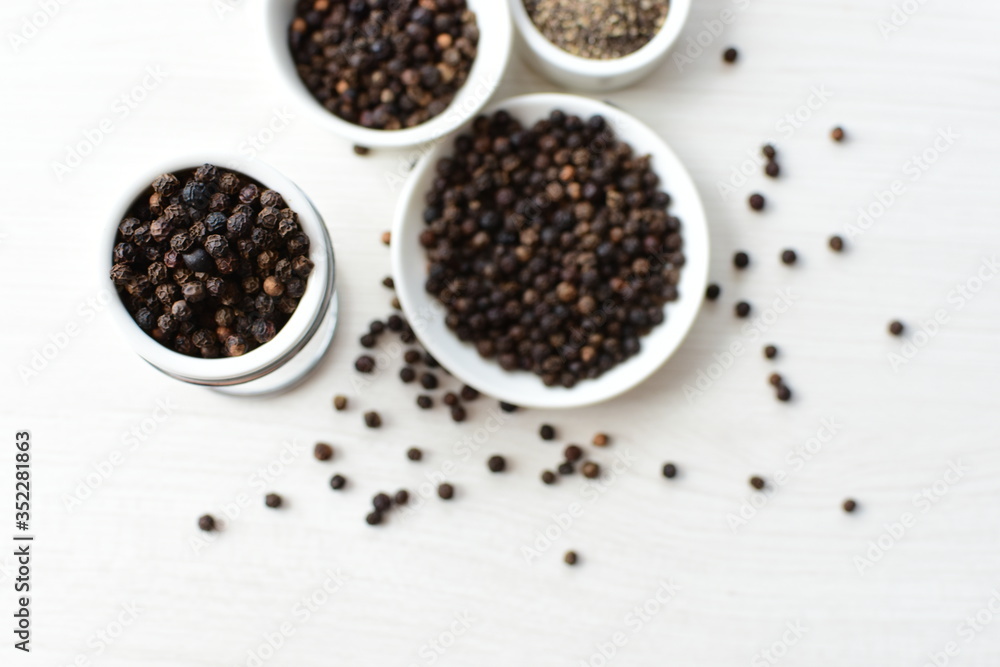 Whole and ground black peppercorns on white wooden background Whole and ground black peppercorns on white wooden background