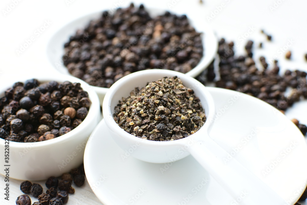 Whole and ground black peppercorns on white wooden background Whole and ground black peppercorns on white wooden background