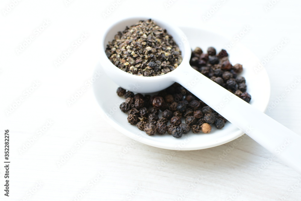 Whole and ground black peppercorns on white wooden background Whole and ground black peppercorns on white wooden background