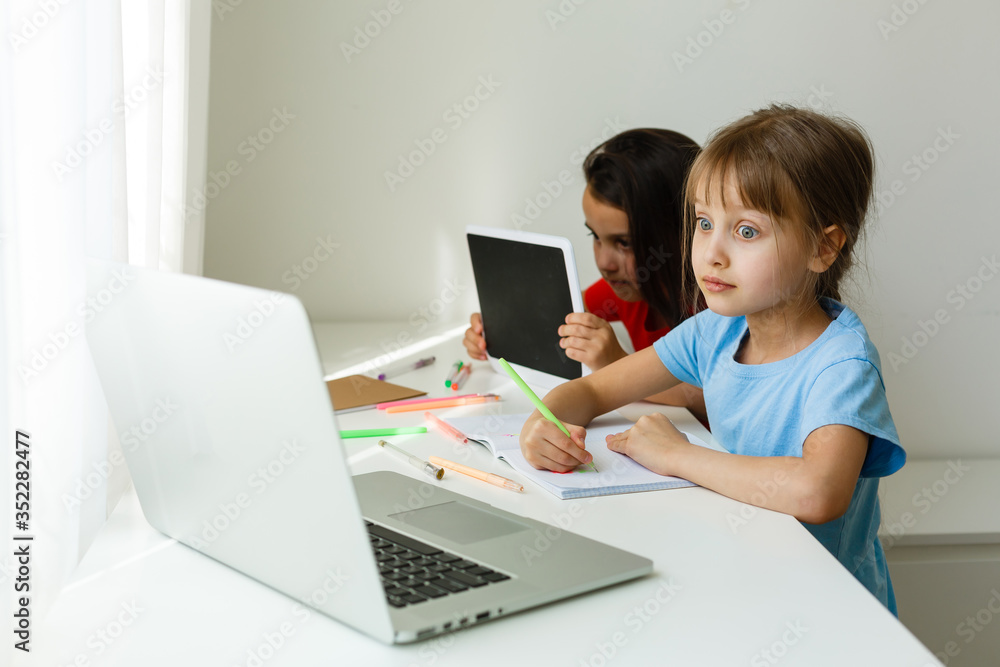 Pretty stylish schoolgirls studying during her online lesson at home, social distance during quarantine, self-isolation, online education concept Pretty stylish schoolgirls studying during her online lesson at home, social distance during quarantine, self-isolation, online education concept