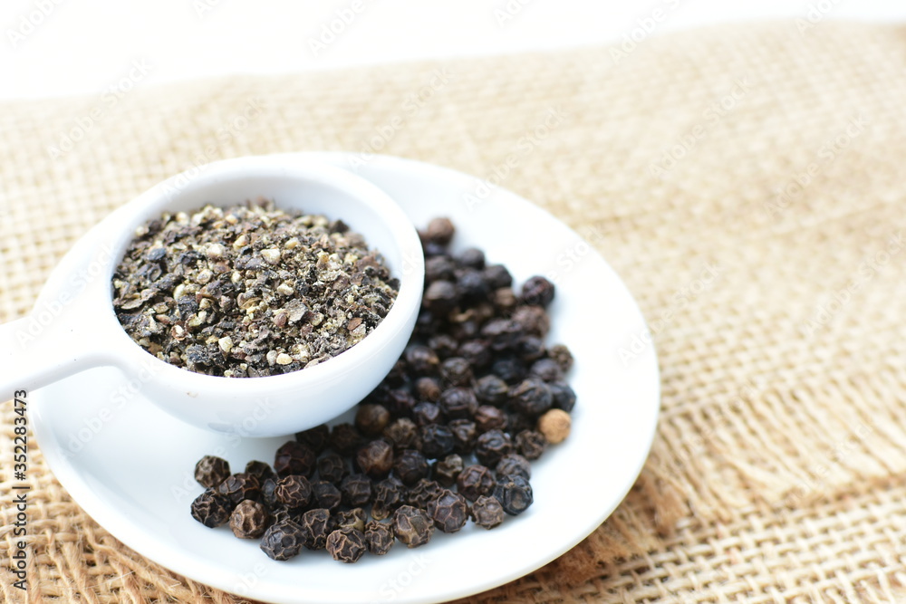 Whole and ground black peppercorns on white wooden background Whole and ground black peppercorns on white wooden background