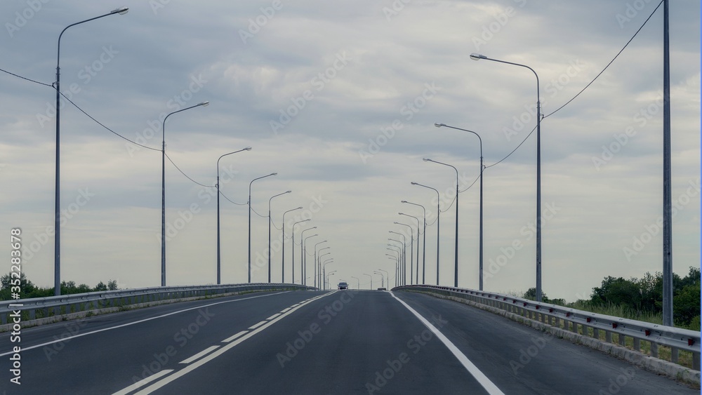 Road. Covering gray asphalt with white markings. By sided pillars of lighting. Road. Covering gray asphalt with white markings. By sided pillars of lighting.