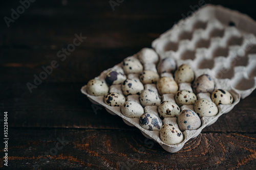 Quail eggs in craft paper box on dark wooden background.  farm products, organic products, Healthy food concept