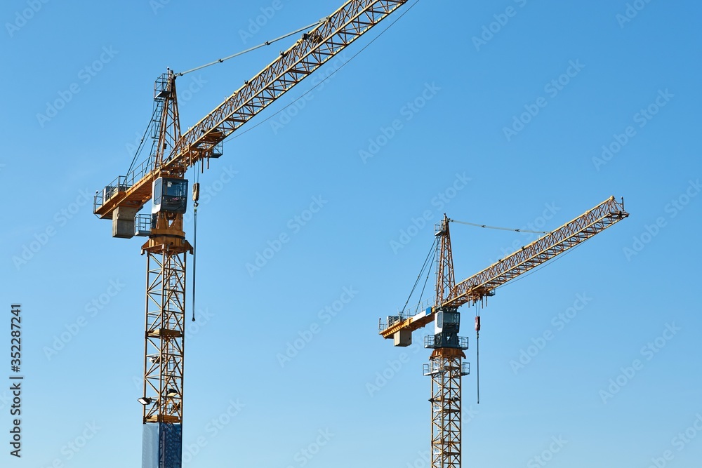 Construction site tower cranes against clear blue sky Construction site tower cranes against clear blue sky
