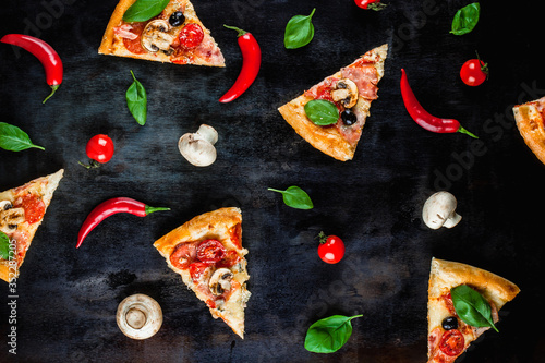 A lot of pieces of pizza with vegetables on a black background. Pizza cooking. Wallpapers with food.