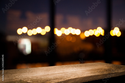 image of wooden table in front of abstract blurred background of restaurant lights