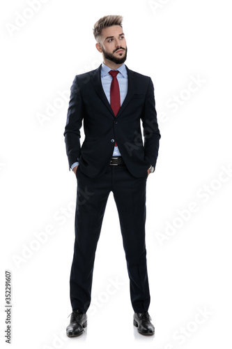 proud businessman looking to side and holding hands in pockets