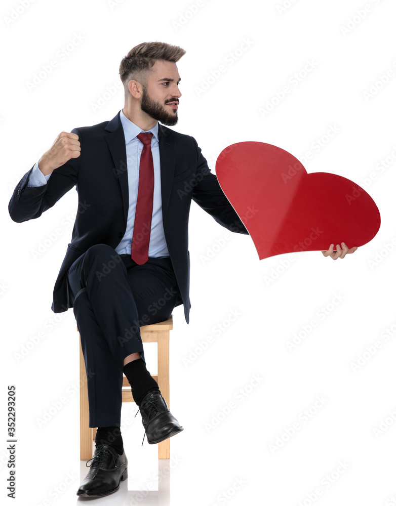 young businessman holding big red heart and punching to side young businessman holding big red heart and punching to side