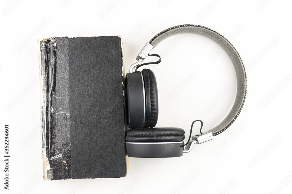 Audio book concept. headphones with book on white background. Listening to book. Modern education. Copyspace. Audio book concept. headphones with book on white background. Listening to book. Modern education. Copyspace.