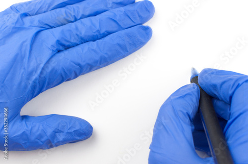A female hand in a medical glove holds a pen and writes in the air on a white background. Copy space for your text