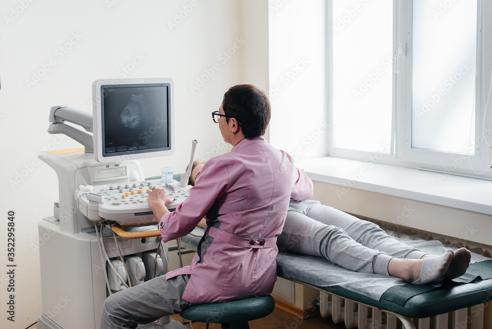 A pregnant girl gets an ultrasound of her abdomen at the clinic. Medical examination A pregnant girl gets an ultrasound of her abdomen at the clinic. Medical examination
