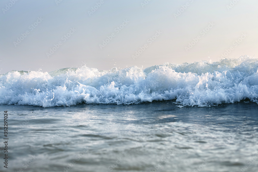 Fototapeta premium sea wave with splashes surges to the beach, against the sky
