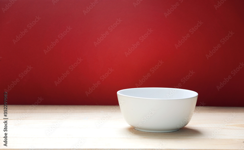 White bowl on wooden table red empty space background.Food backdrop. White bowl on wooden table red empty space background.Food backdrop.